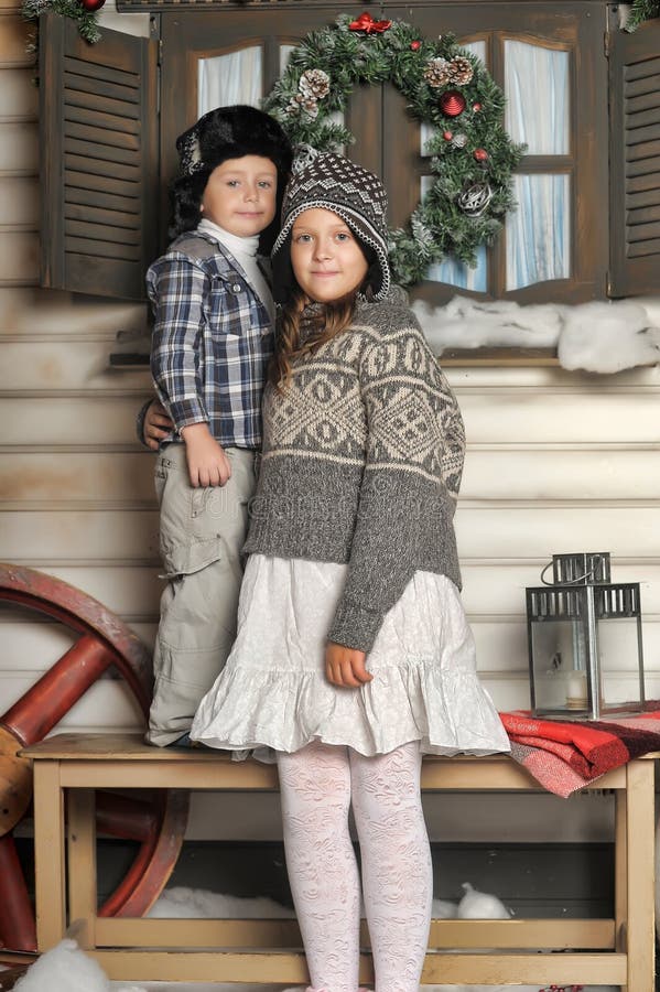 Brother and sister on a bench in front of the house in winter