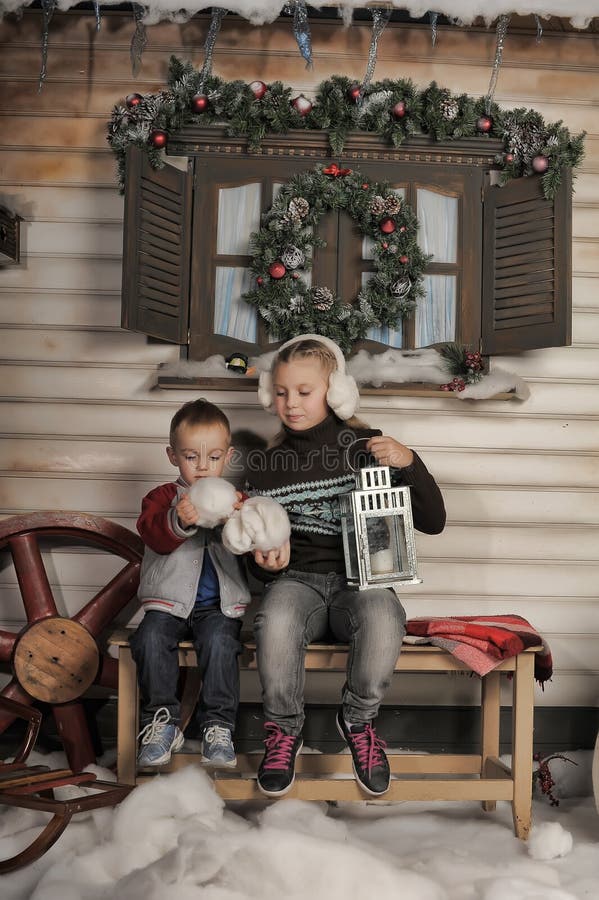 Brother and sister on a bench in front of the house in winter