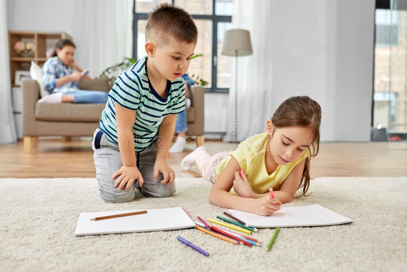 Brother And Sister Drawing With Crayons At Home Stock