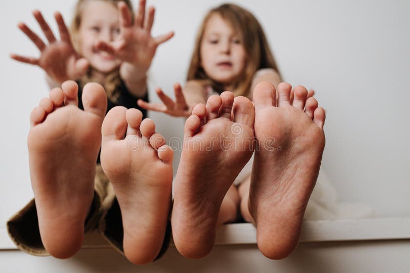 Children`s feet close up to the camera. Their blurred faces in a background.