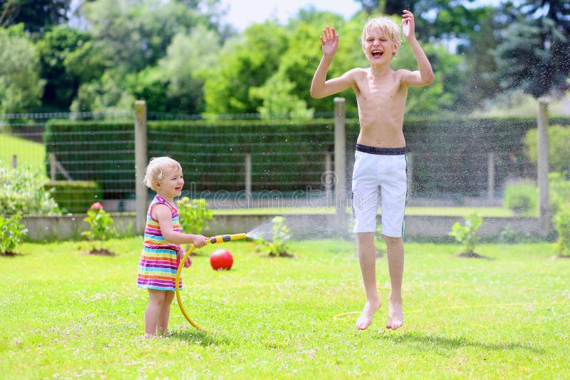 Brother and sister playing with water hose in the garden royalty free stock image Brother and sister playing with water hose in the garden royalty free stock image