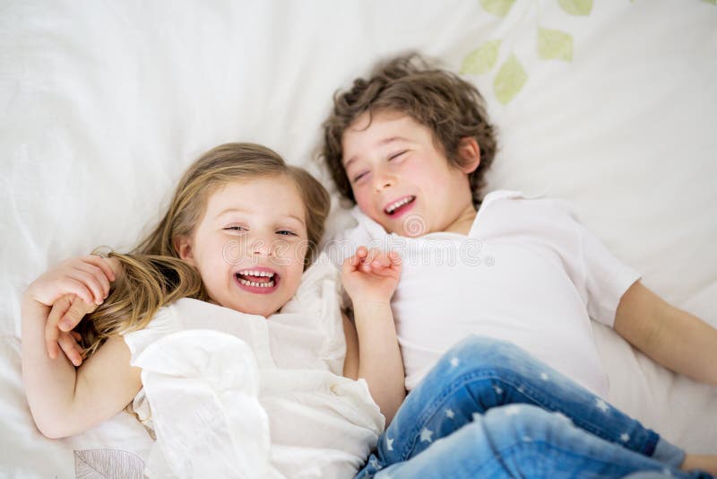 Brother And Sister Relaxing Together In Bed. 