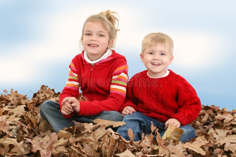 Brother and Sister Sitting in Pile of Leaves