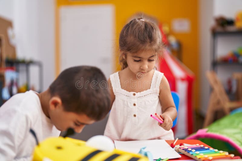 Brother and Sister Students Sitting on Table Drawing on Paper at