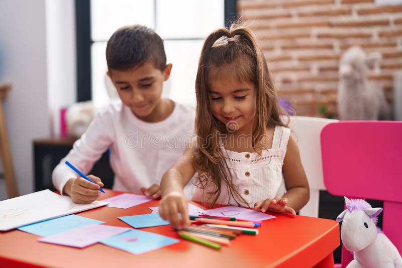 Brother and Sister Students Sitting on Table Drawing on Paper at