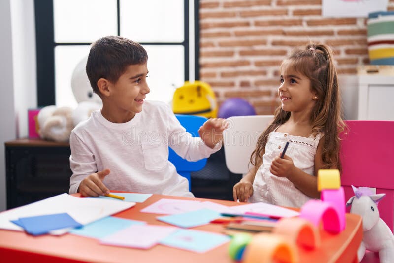 Brother and Sister Students Sitting on Table Drawing on Paper at