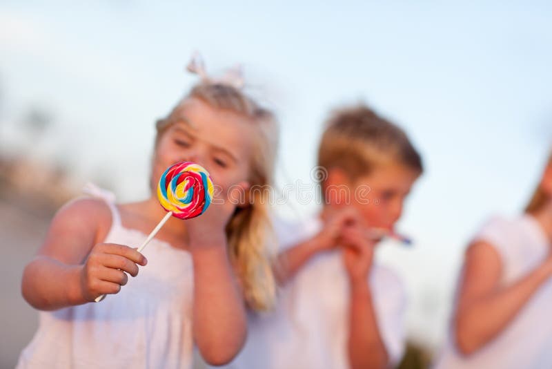 Brother and Sisters Enjoying Their Lollipops Outsi