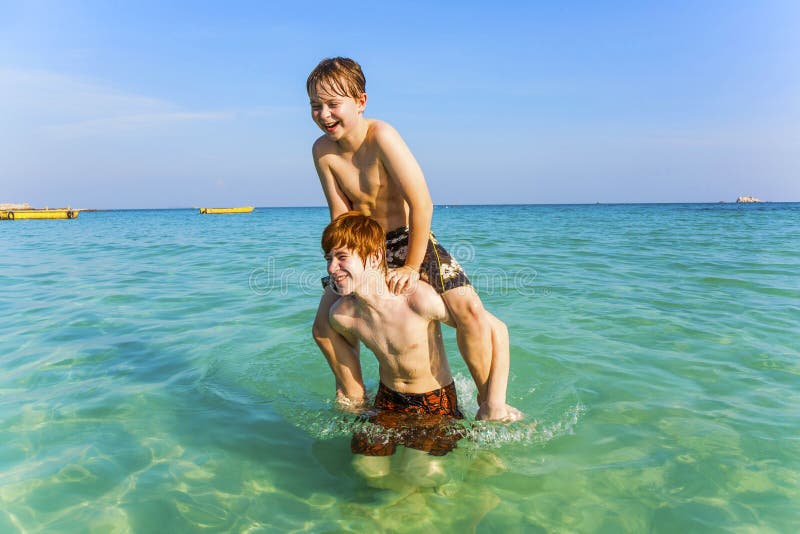 Brothers are enjoying the clear warm water in the ocean and play