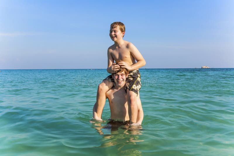 Brothers are enjoying the clear warm water in the ocean and play