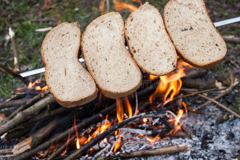 Brotröstung auf dem Feuer lizenzfreie stockbilder Brotröstung auf dem Feuer lizenzfreie stockbilder