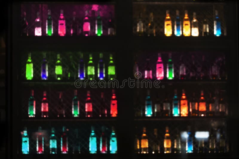 Brouillez la lampe au néon rougeoyante de la bouteille potable d'alcool dans la barre ou du bar pour le fond foncé de partie de n images stock Brouillez la lampe au néon rougeoyante de la bouteille potable d'alcool dans la barre ou du bar pour le fond foncé de partie de n images stock