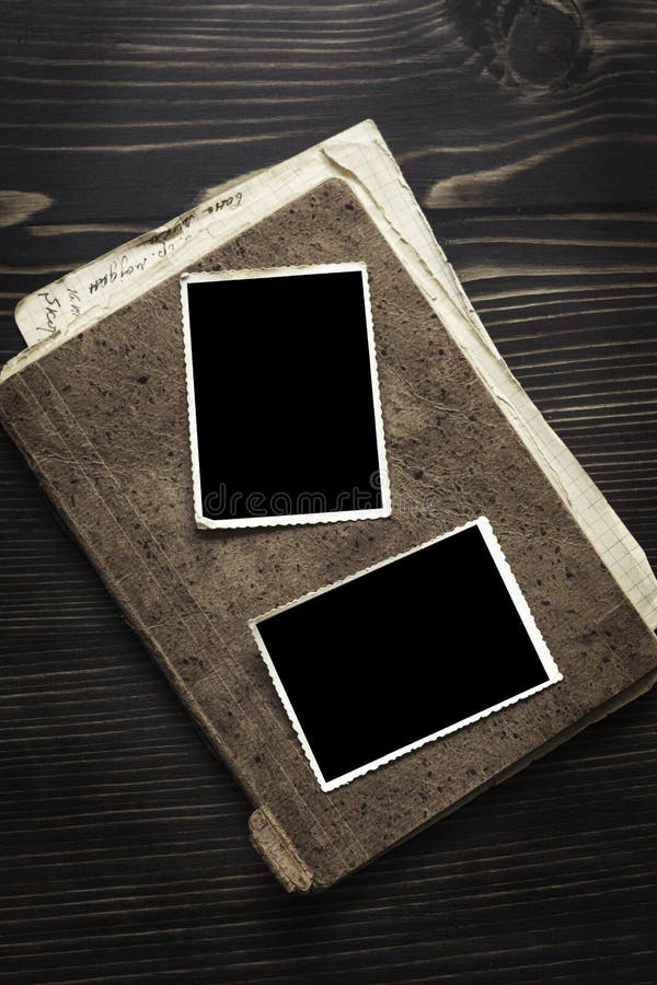 Brown book with old frame photo on wood table background