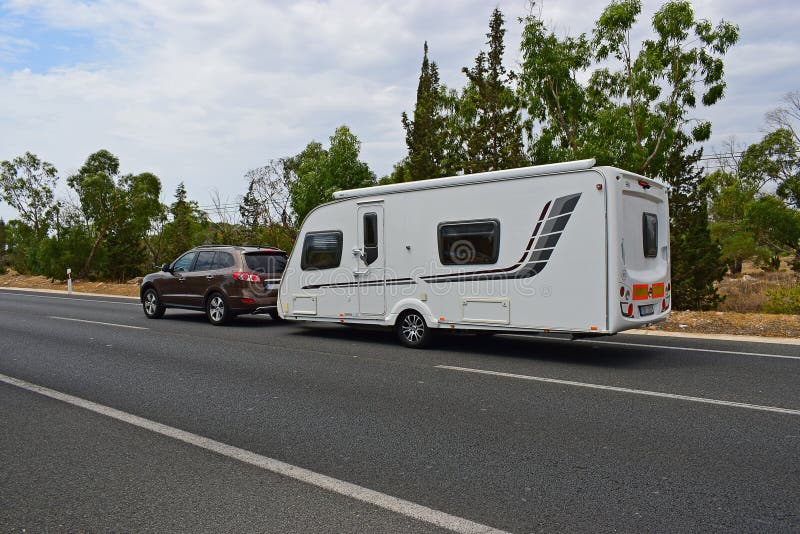 Car Towing A Caravan. A brown car towing a large caravan on an empty road royalty free stock image