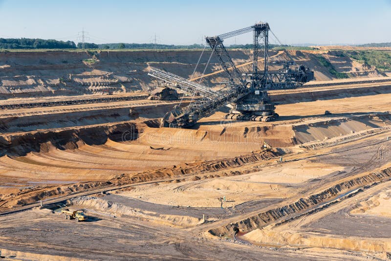 Brown coal open pit landscape with digging excavator in Germany stock images