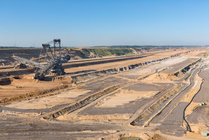 Brown coal open pit landscape with digging excavator in Germany royalty free stock image