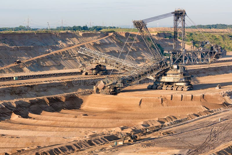 Brown coal open pit landscape with digging excavator in Germany royalty free stock images