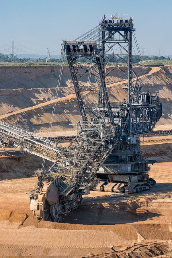 Brown coal open pit landscape with digging excavator in Germany royalty free stock image