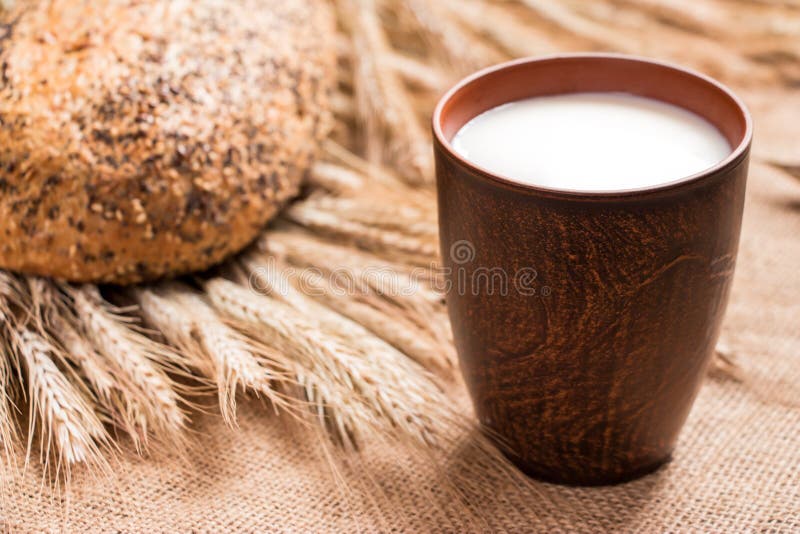 Brown Cup of Milk, a Loaf of Bread, Wheat Spikelets . Stock Photo