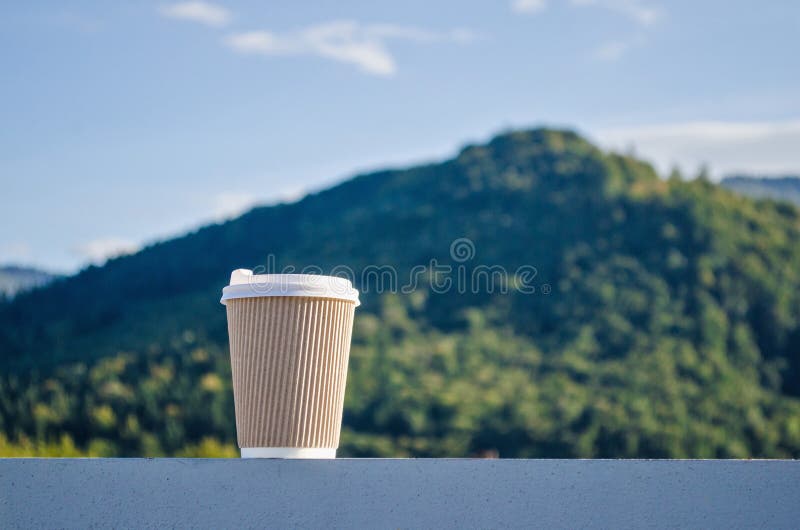 Brown Disposable Cup of Coffee on Background of Green Carpathian