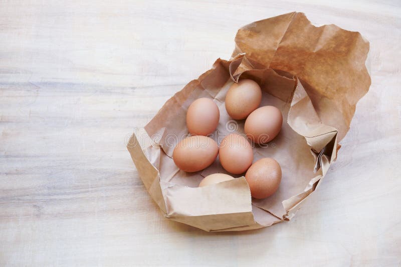 Brown Egg in Paper Bag Behind on a Light Colored Background,Fresh