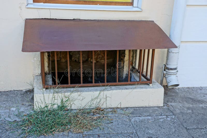 Brown iron grating on an old cellar window on the wall near the sidewalk stock photo Brown iron grating on an old cellar window on the wall near the sidewalk stock photo