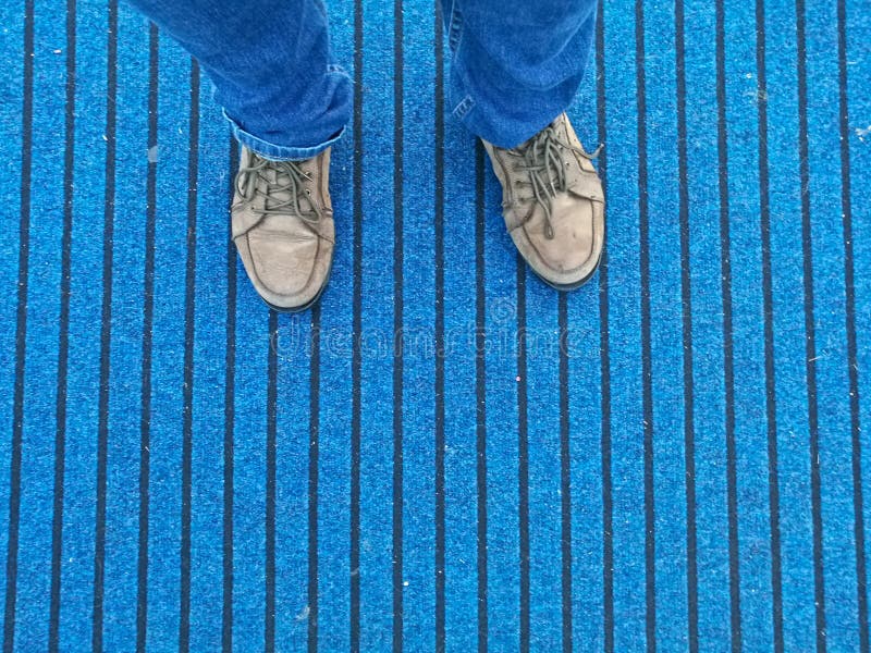 Brown leather shoes with jeans standing on blue carpet stock photo Brown leather shoes with jeans standing on blue carpet stock photo