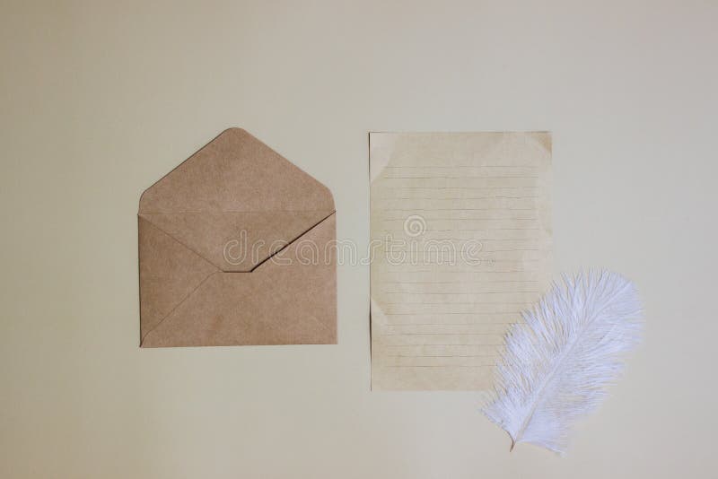 A brown letter and envelope with white feather over the brown background. stock photos