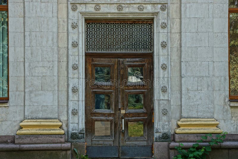 Brown old door of wood and glass on a gray concrete wall with columns royalty free stock photo Brown old door of wood and glass on a gray concrete wall with columns royalty free stock photo