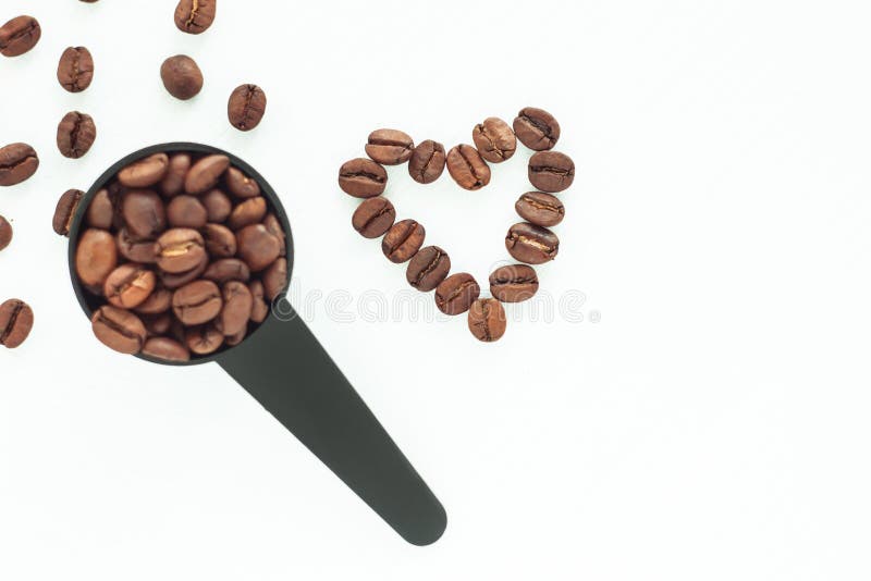 Brown piec kawowe fasole w czarnej pomiarowej łyżce na białym tle odizolowywającym obraz royalty free Brown piec kawowe fasole w czarnej pomiarowej łyżce na białym tle odizolowywającym obraz royalty free