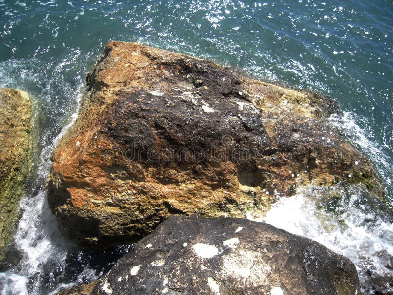 Brown sea rocks on the seaside and glitter shiny wave royalty free stock photo Brown sea rocks on the seaside and glitter shiny wave royalty free stock photo