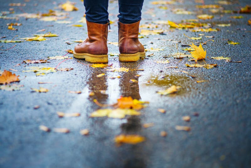 Brown shoes on wet sidewalk in autumn