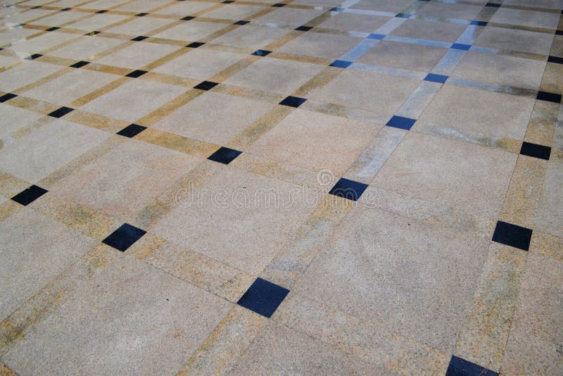 Brown smooth tile with a pattern of squares, close-up near the fountain. royalty free stock images
