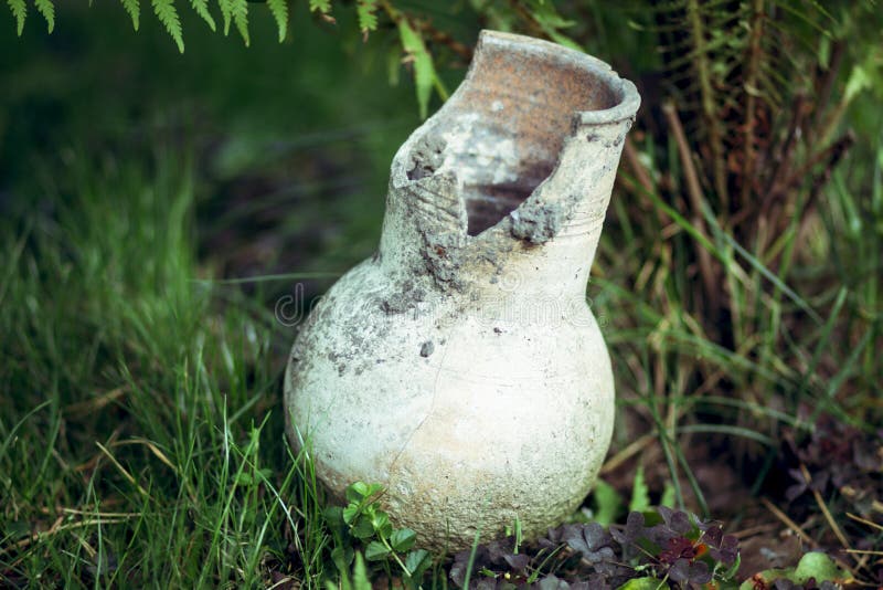 Brown traditional Russian broken clay milk jug on the grass stock image