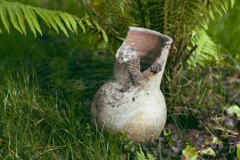 Brown traditional Russian broken clay milk jug on the grass royalty free stock photo