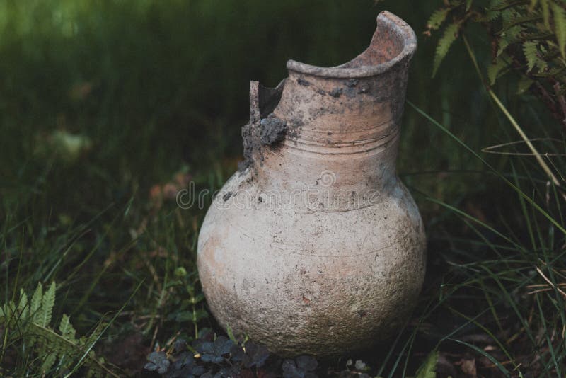 Brown traditional Russian broken clay milk jug on the grass stock image