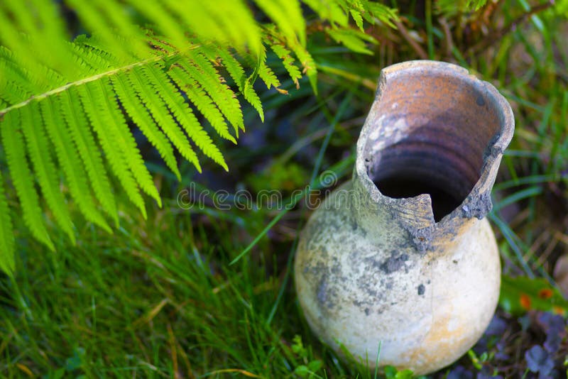 Brown traditional Russian broken clay milk jug on the grass royalty free stock photos