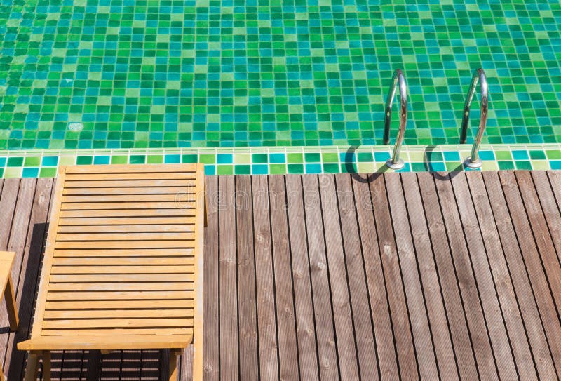 Brown wooden chairs side swimming pool.