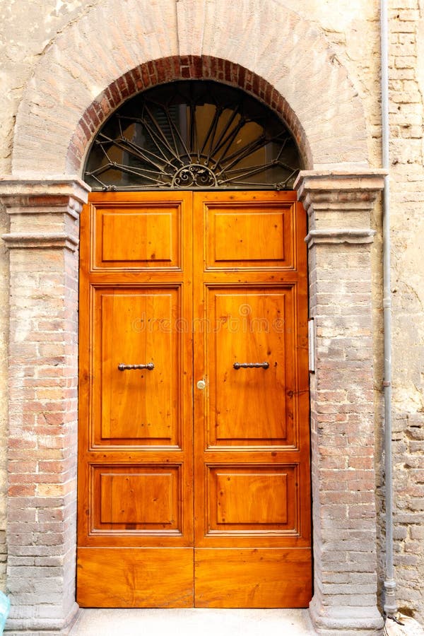 Brown wooden doors in a stone archway wall royalty free stock image