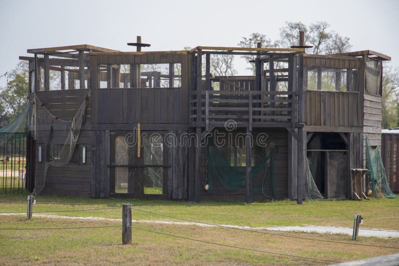 A brown wooden structure surrounded by lush green tress and grass at Old Fort Jackson in Savannah Georgia