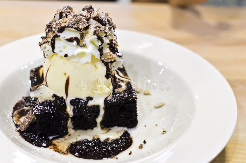 Brownie dessert on a white plate with chocolate syrup and vanilla ice cream. pecans on the top. royalty free stock photos