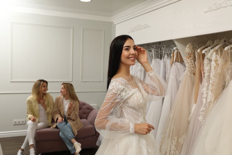 Brud med vänner som väljer bröllopsklänning i boutique arkivbild