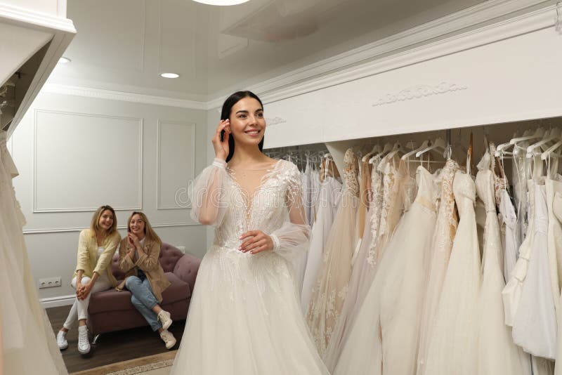 Brud med vänner som väljer bröllopsklänning i boutique fotografering för bildbyråer