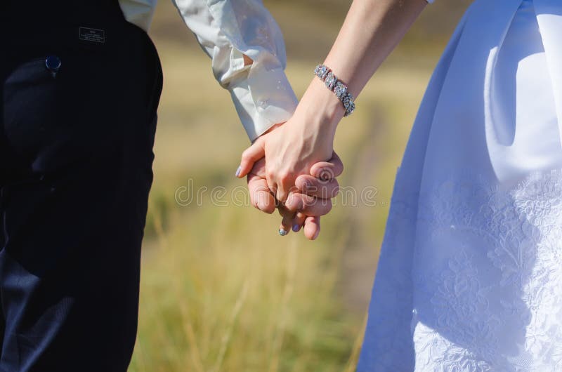 Brud och brudgum som rymmer sig händer arkivfoto Brud och brudgum som rymmer sig händer arkivfoto