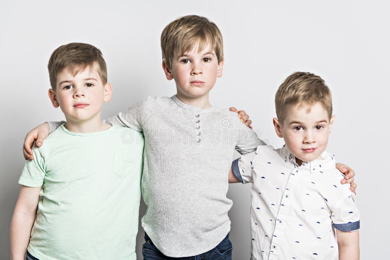 Bruder mit drei Freunden zusammen auf weißem Hintergrund des Studios stockfotografie