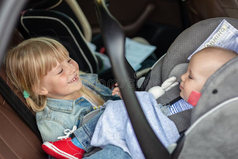 Bruder und Schwester, die im Auto im Sicherheitssitz sitzen Geschwister auf den Passagierplätzen, die Spaß zusammen während der R stockbild Bruder und Schwester, die im Auto im Sicherheitssitz sitzen Geschwister auf den Passagierplätzen, die Spaß zusammen während der R stockbild