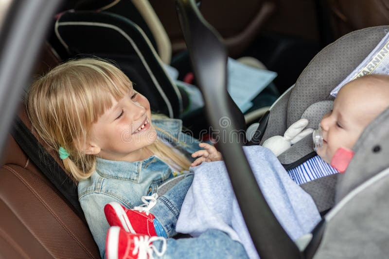 Bruder und Schwester, die im Auto im Sicherheitssitz sitzen Geschwister auf den Passagierplätzen, die Spaß zusammen während der R stockfotos Bruder und Schwester, die im Auto im Sicherheitssitz sitzen Geschwister auf den Passagierplätzen, die Spaß zusammen während der R stockfotos