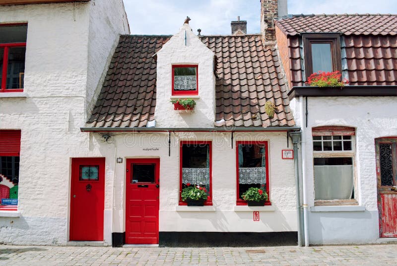 Bruges, Belgique - août 2010 : Petites maisons blanches pittoresques avec les portes rouges, les châssis de fenêtre rouges, les f images stock Bruges, Belgique - août 2010 : Petites maisons blanches pittoresques avec les portes rouges, les châssis de fenêtre rouges, les f images stock