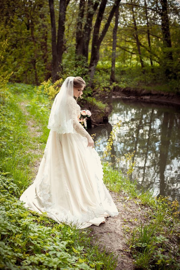Bruid in een witte kleding op de achtergrond van aard Huwelijksfotografie royalty-vrije stock foto Bruid in een witte kleding op de achtergrond van aard Huwelijksfotografie royalty-vrije stock foto
