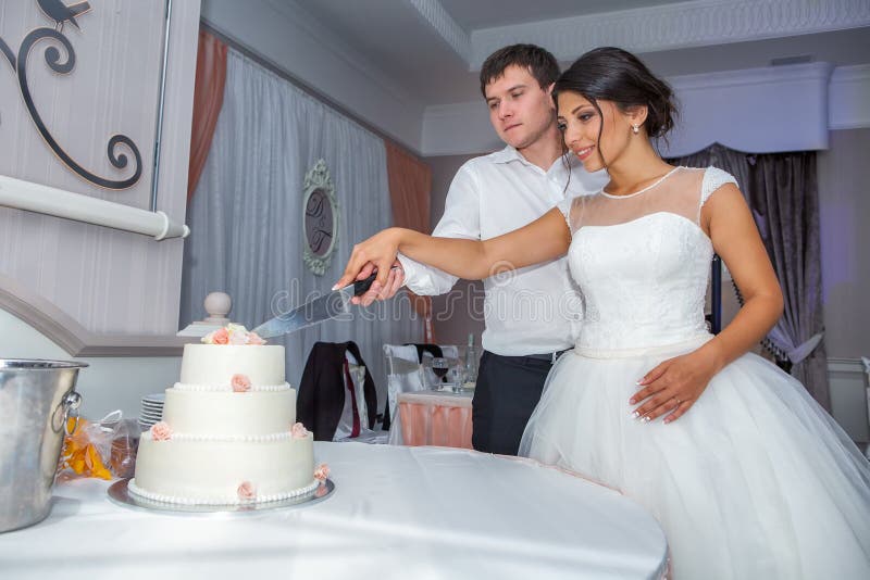 Bruid en Bruidegom bij Huwelijksontvangst die de Huwelijkscake snijden stock fotografie Bruid en Bruidegom bij Huwelijksontvangst die de Huwelijkscake snijden stock fotografie