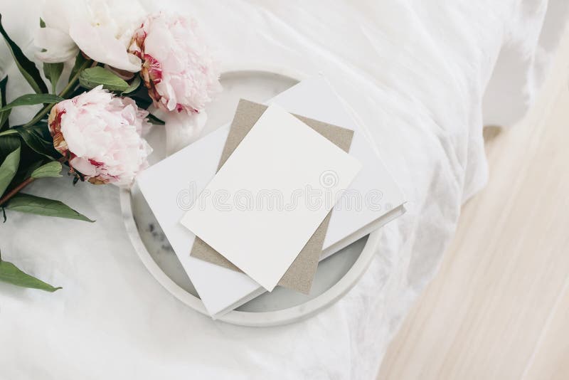 Bruiloft nog levenscène. groet card mockup scènes papierenvelop op marmer dienblad. roze pony bloemen op